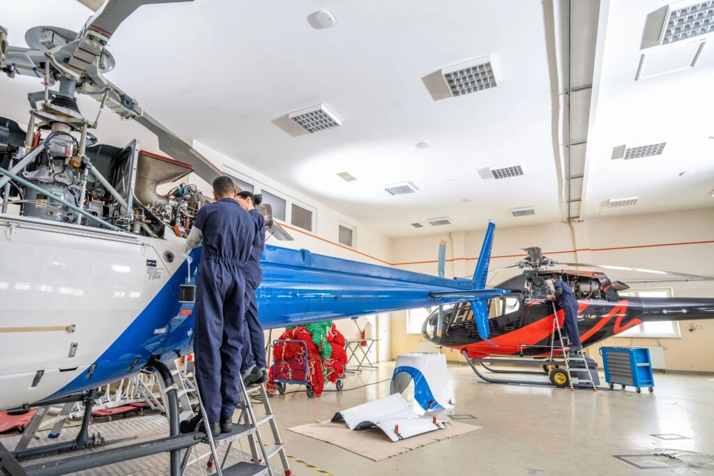 Aircraft mechanics standing on ladder and repairing propeller engine